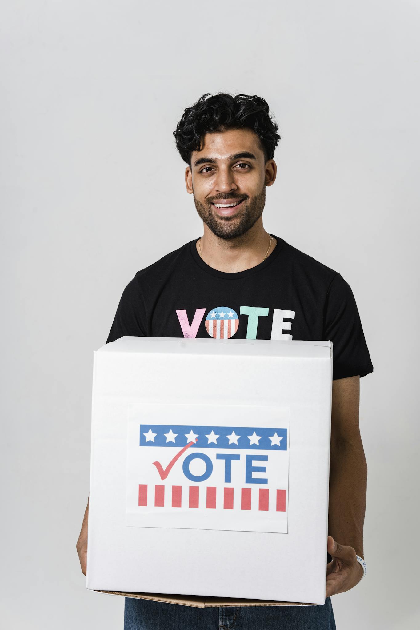 Smiling young man holding a vote box, promoting voting and civic engagement.